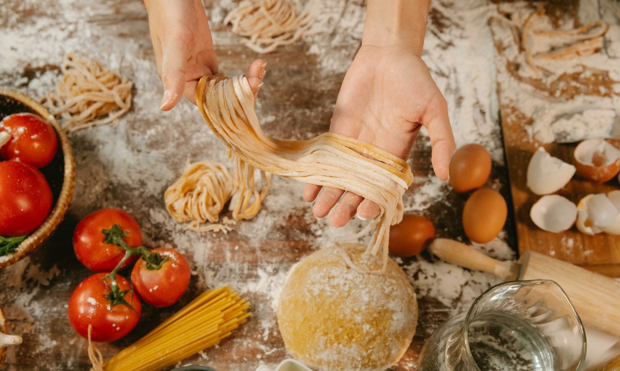 Bild von frischer Pasta, die gerade gemacht wurde und in den Händen gehalten wird.